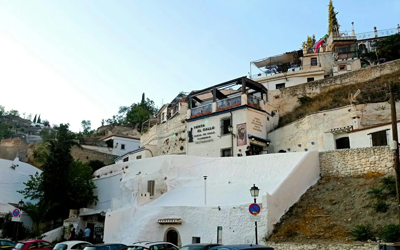 White cave houses in Sacromonte, Granada, with a view of Venta El Gallo flamenco venue.