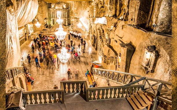 Wieliczka Salt Mine chamber with chandeliers and tourists exploring the historic site.