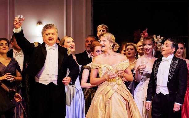 Opera performers in elegant attire during La Traviata at Sydney Opera House.