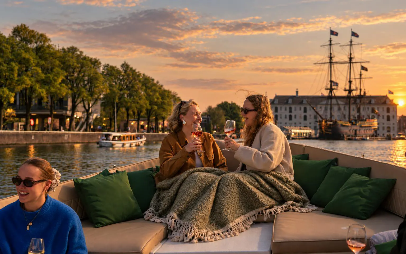 Evening canal cruise in Amsterdam with people enjoying drinks on an open electric boat.