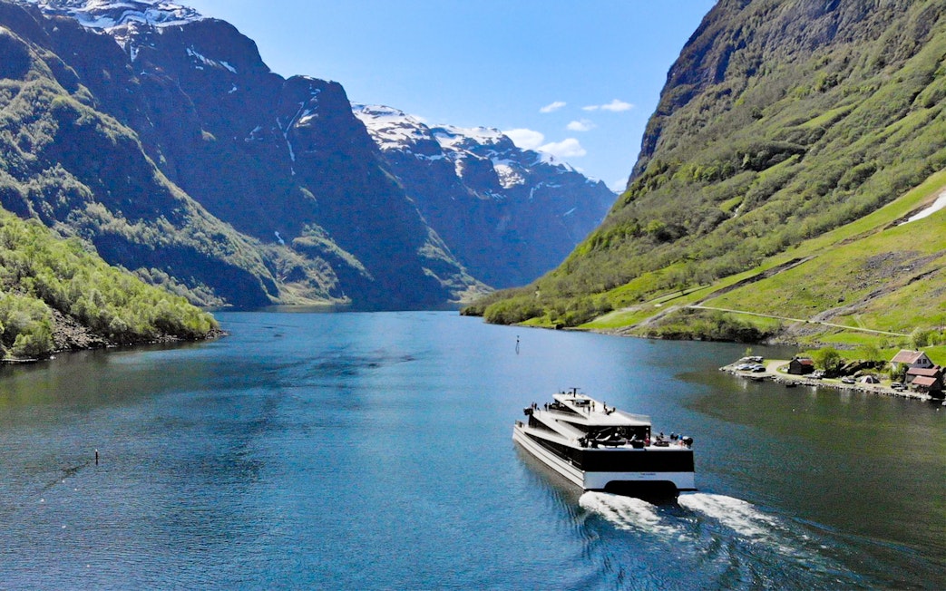 Cruise ship on Nærøyfjord surrounded by steep mountains, Norway.