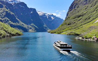 Cruise ship on Nærøyfjord surrounded by steep mountains, Norway.