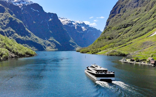 Cruise ship on Nærøyfjord surrounded by steep mountains, Norway.