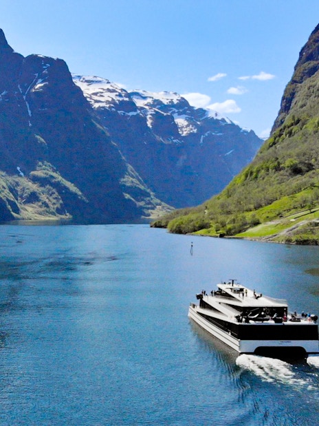 Cruise ship on Nærøyfjord surrounded by steep mountains, Norway.