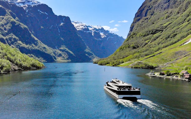 Cruise ship on Nærøyfjord surrounded by steep mountains, Norway.