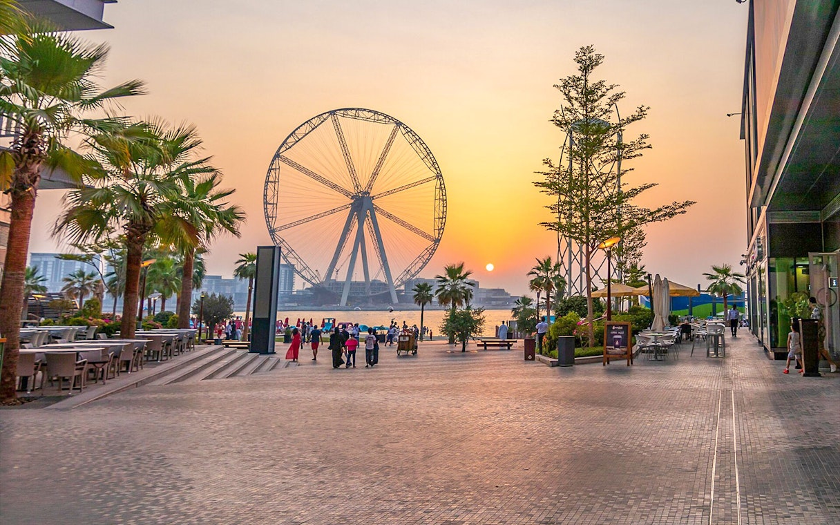 Dubai promenade with Ain Dubai Ferris wheel at sunset.