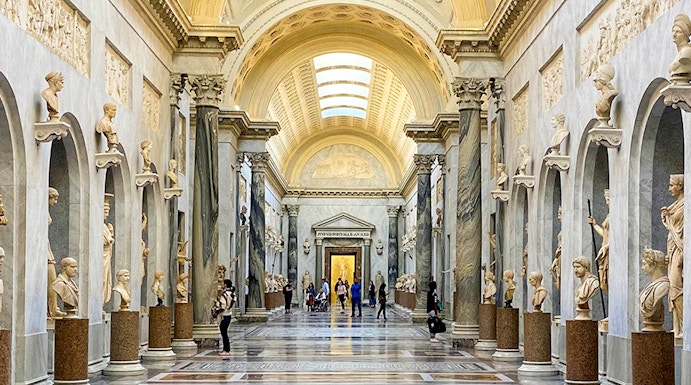 Vatican Museums gallery with ornate ceiling and classical statues, Rome.