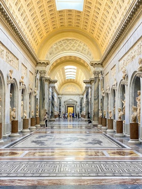 Vatican Museums gallery with ornate ceiling and classical statues, Rome.