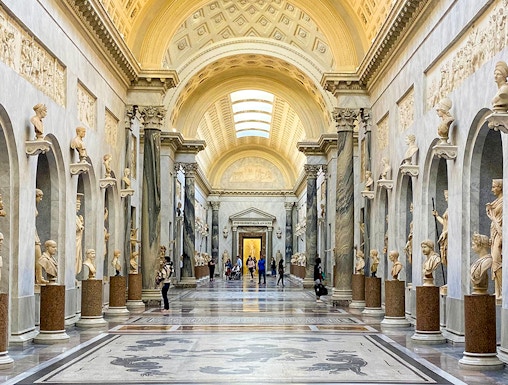 Vatican Museums gallery with ornate ceiling and classical statues, Rome.