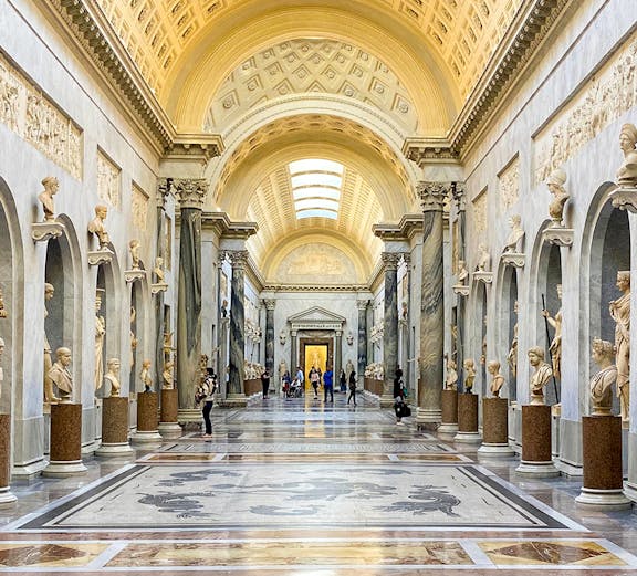 Vatican Museums gallery with ornate ceiling and classical statues, Rome.