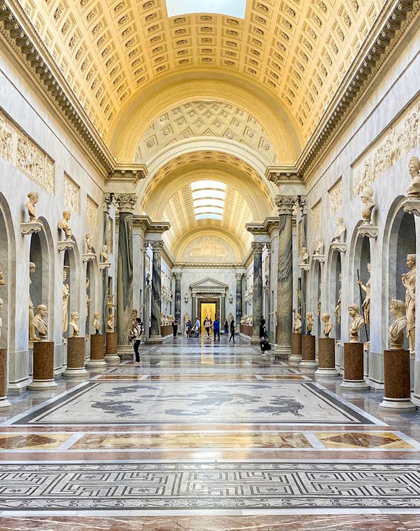 Vatican Museums gallery with ornate ceiling and classical statues, Rome.
