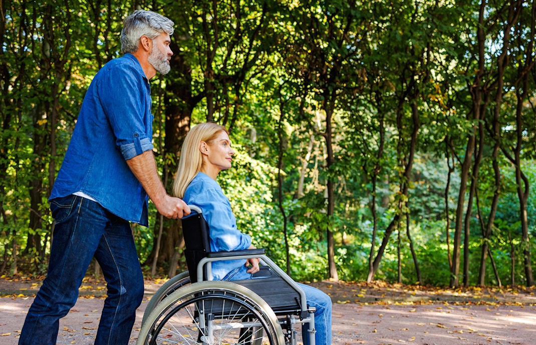 Man pushing woman in wheelchair along Jardin Secret path.