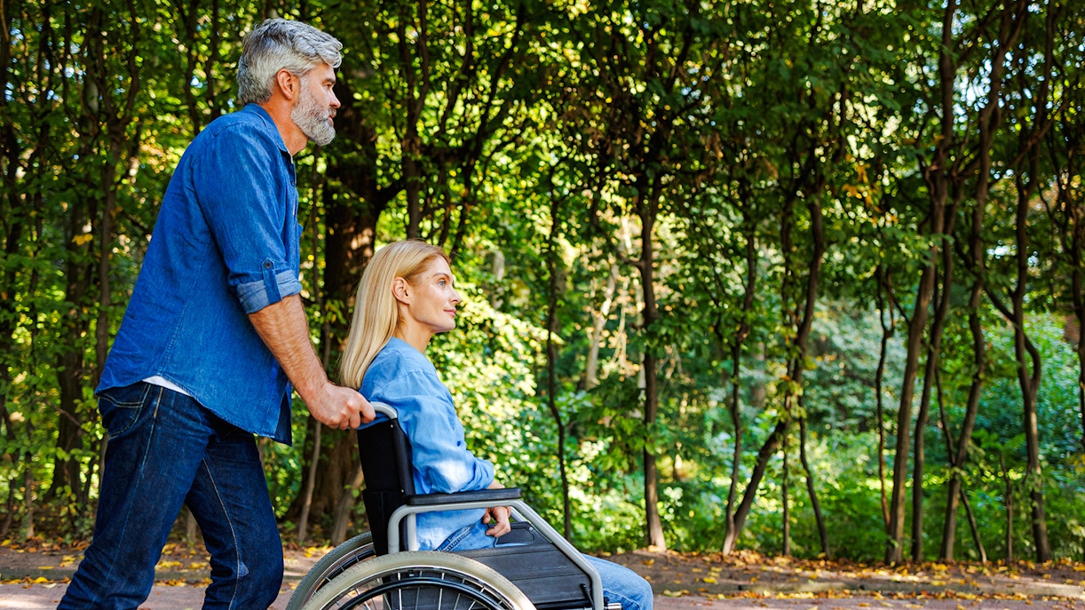 Man pushing woman in wheelchair along Jardin Secret path.