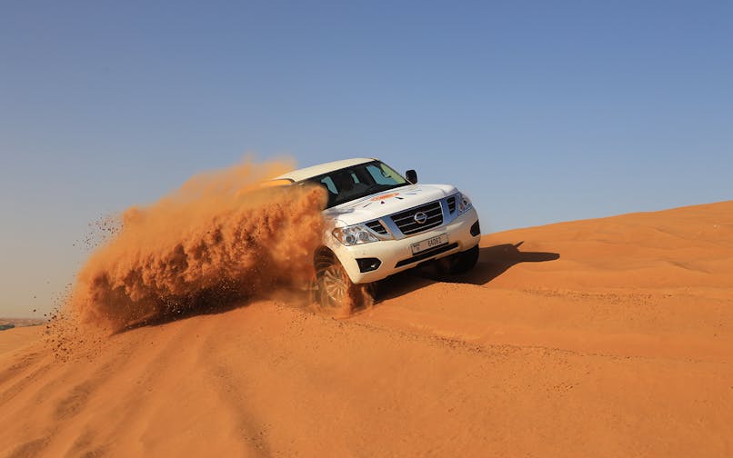SUV driving through Arabian desert dunes during premium safari experience.