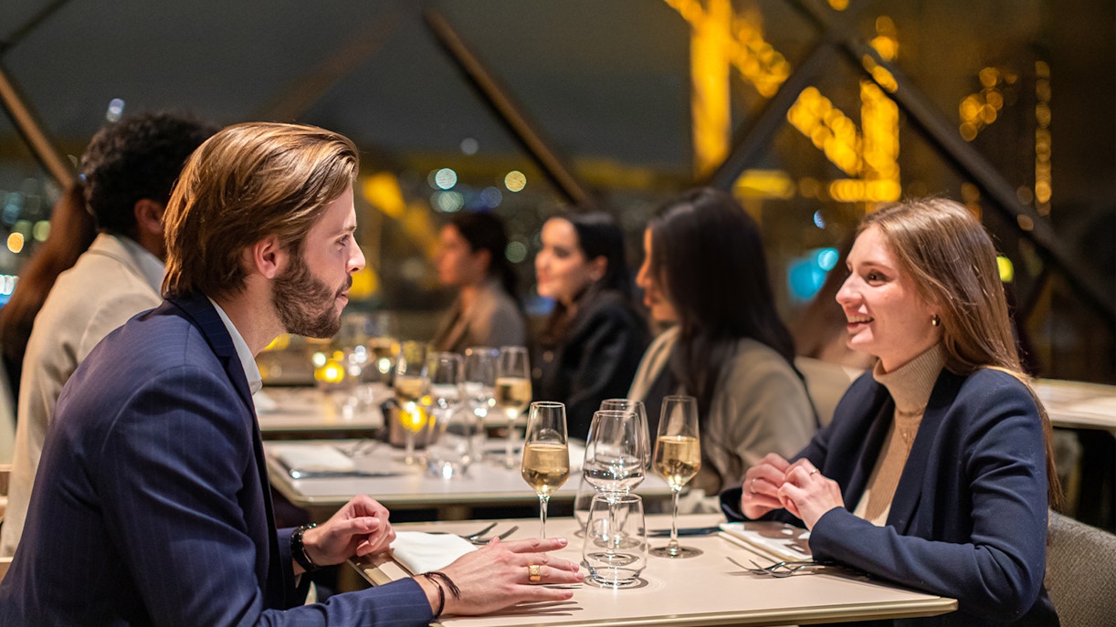 Young couple dining at Madame Brasserie Restaurant with Eiffel Tower view.