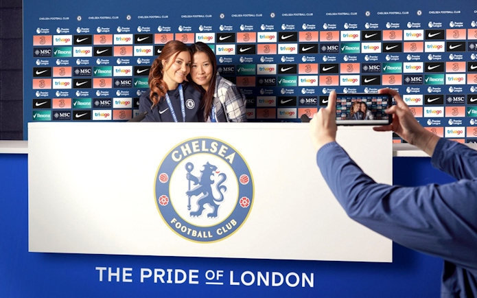 Chelsea FC press room with visitors posing for a photo during stadium tour.
