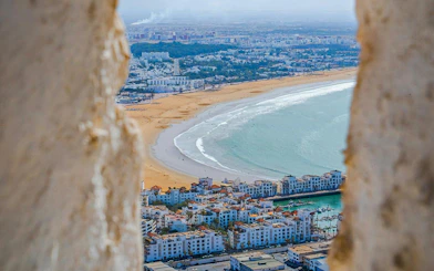 Aerial view of Agadir beach and cityscape framed by ancient walls.