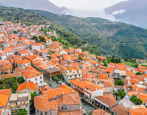 Aerial view of Arachova village with red-tiled roofs and surrounding mountains near Delphi Archaeological Site.