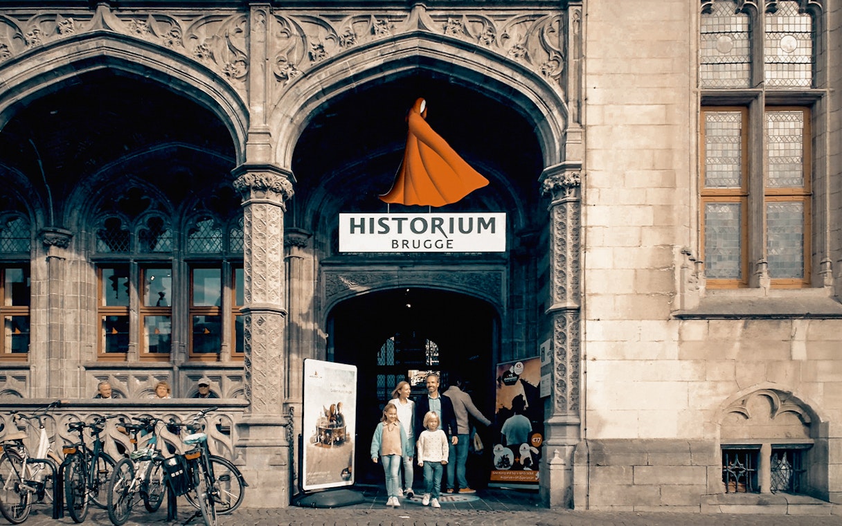 Family standing at the entrance of Historium Bruges, Belgium.