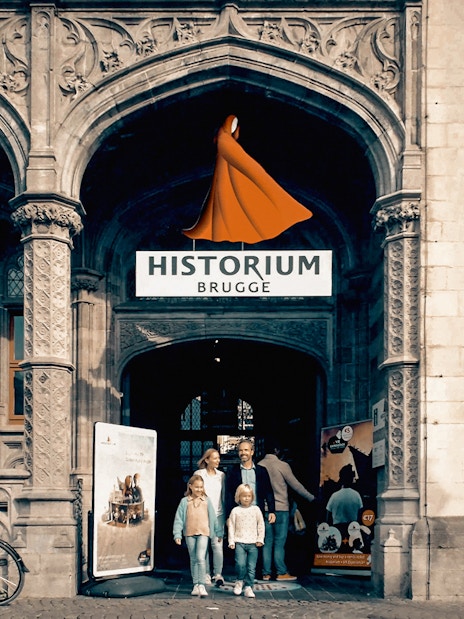 Family standing at the entrance of Historium Bruges, Belgium.