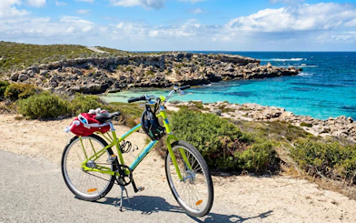 Bicycle parked by the turquoise waters and rocky coastline of Rottnest Island.