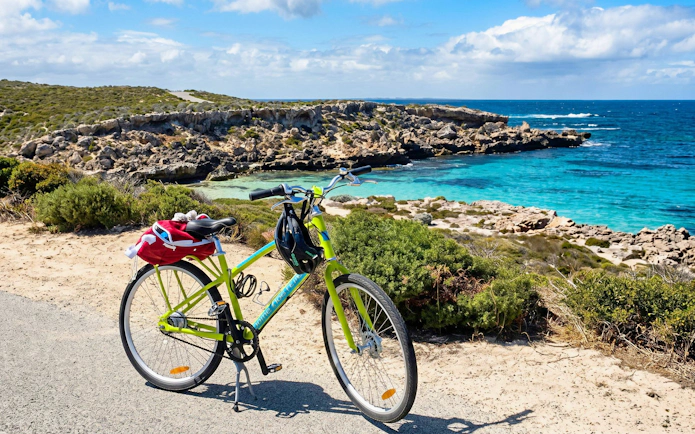 Bicycle parked by the turquoise waters and rocky coastline of Rottnest Island.