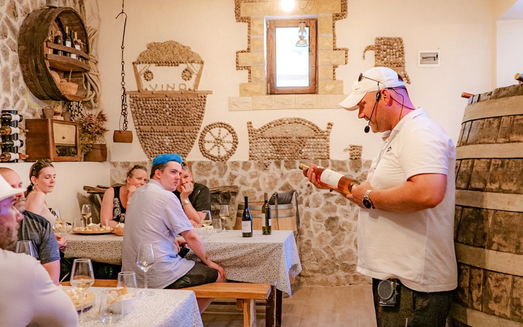 Tour guide explaining wine details to visitors at Krka National Park tasting room.