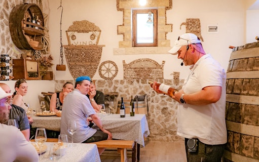 Tour guide explaining wine details to visitors at Krka National Park tasting room.
