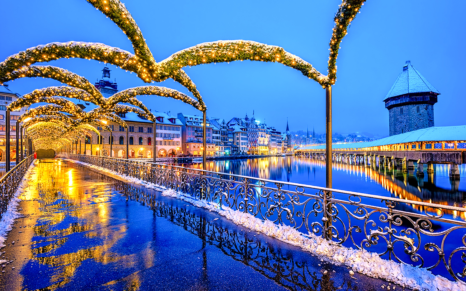 Lucerne Old Town bridge with Christmas lights reflecting on wet pavement, Switzerland.