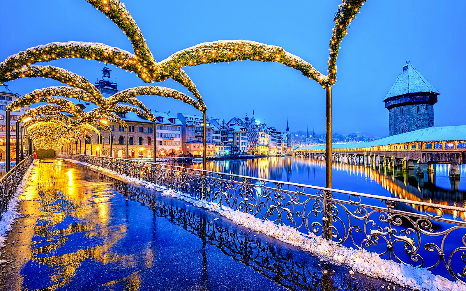 Lucerne Old Town bridge with Christmas lights reflecting on wet pavement, Switzerland.