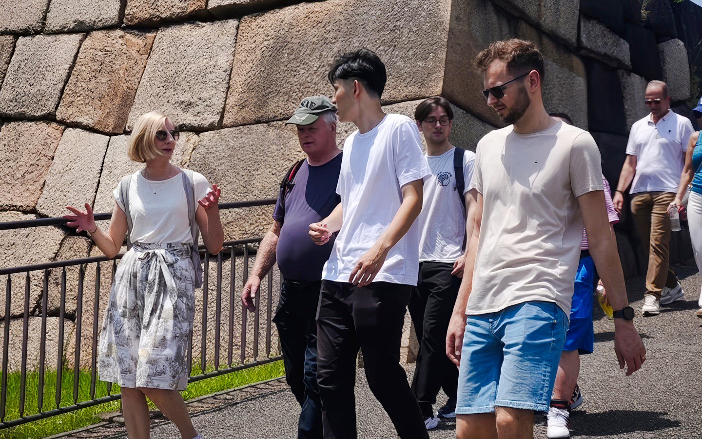 Tour group walking near the stone walls of Tokyo's Imperial Palace.