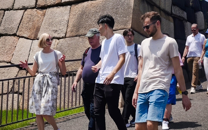 Tour group walking near the stone walls of Tokyo's Imperial Palace.