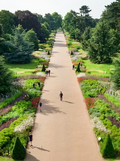 Pathway through vibrant gardens at Kew Gardens, London, with visitors strolling.