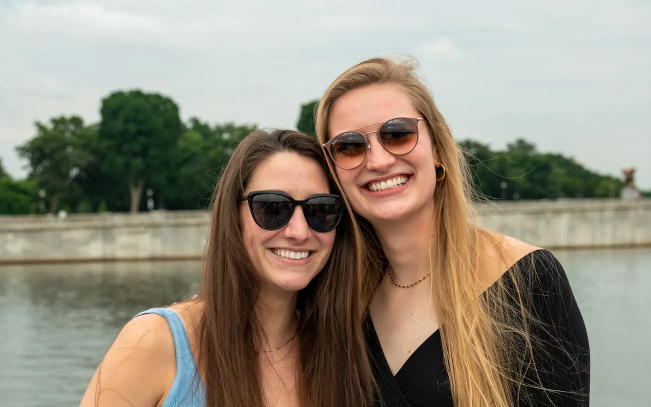 Two people smiling on a Potomac River cruise with DC landmarks in the background.