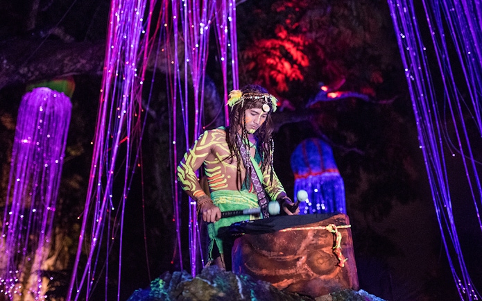 Performer in neon body paint playing drums at Sunway Lost World of Tambun, Malaysia.