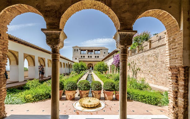Alhambra courtyard with arches and garden, view of Nasrid Palaces, Granada.