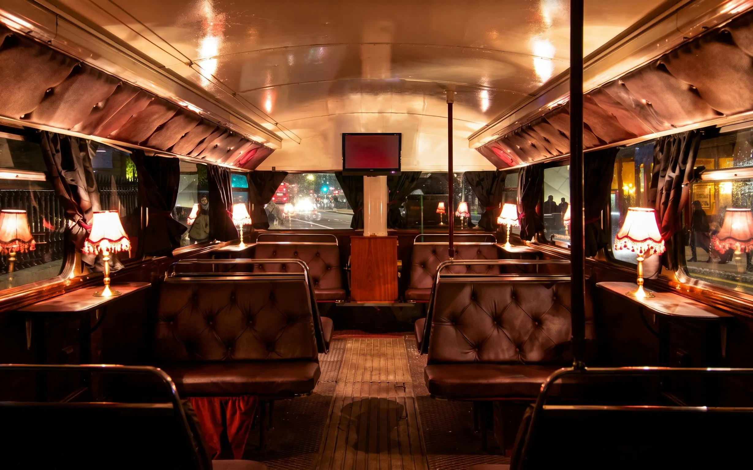 Interior of a vintage bus with dim lighting and plush seating on the London ghost bus tour.