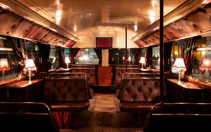 Interior of a vintage bus with dim lighting and plush seating on the London ghost bus tour.
