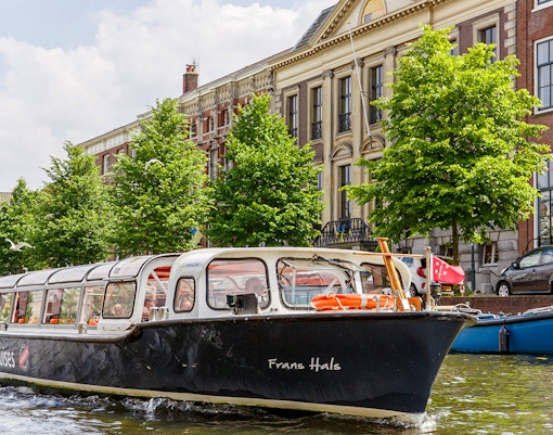 Canal boat cruising past historic buildings in Haarlem.