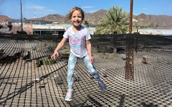 Child enjoying trampoline at Hatta Wadi Hub with mountains in the background.