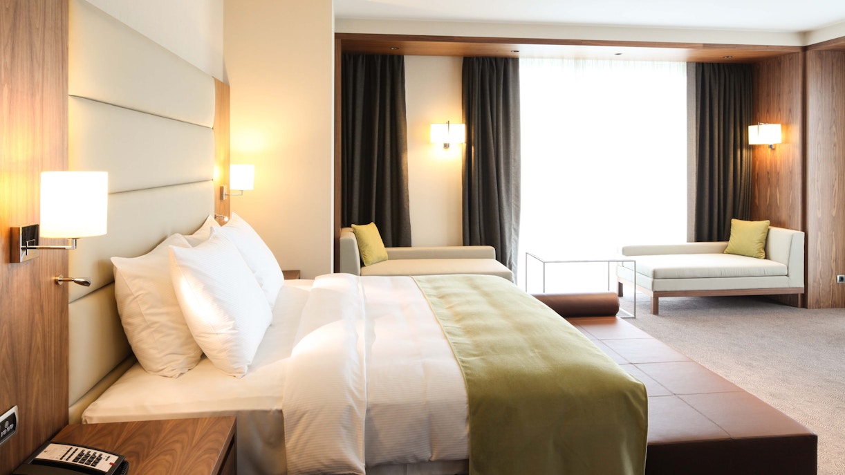 Modern hotel room with a large bed, seating area, and natural light in Penang.