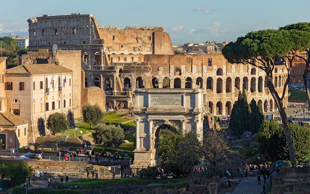 Colosseum and Arch of Constantine in Rome with surrounding greenery.