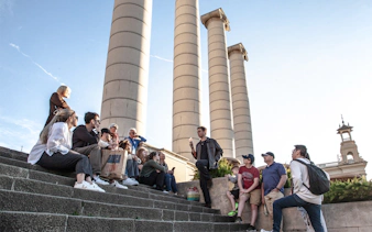 Group listening to a guide near Montjuïc columns in Barcelona.