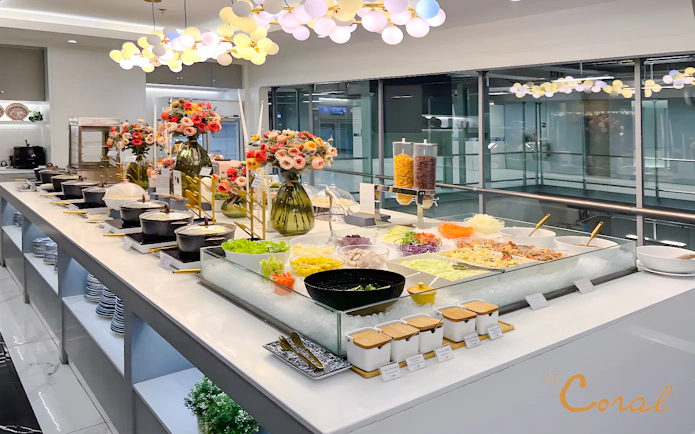 Buffet spread at Coral Finest Business Class Lounge, Bangkok airport, featuring salads and hot dishes.