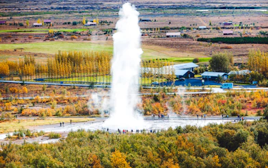 Geyser eruption in Iceland's Golden Circle with tourists nearby, part of Reykjavik day tour.