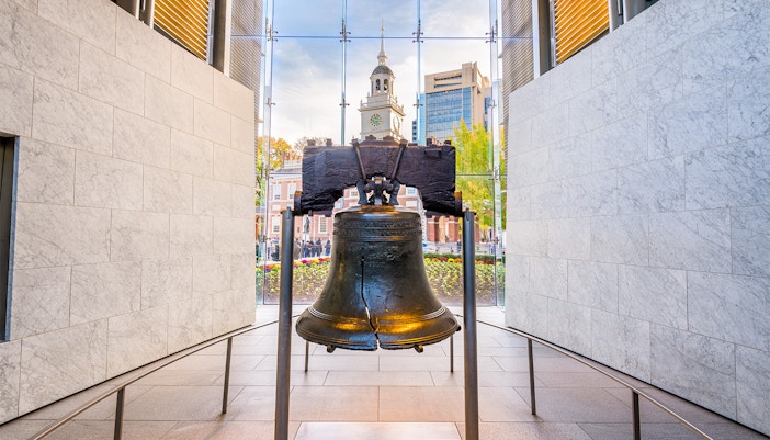 Liberty Bell with Independence Hall in Philadelphia background.