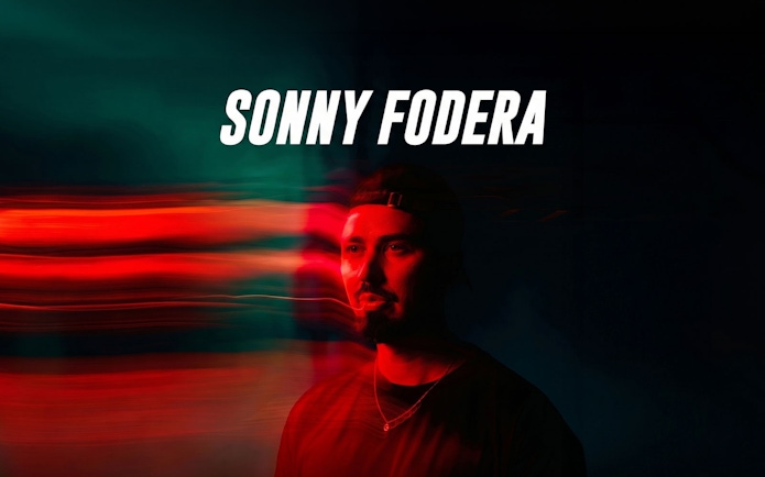 Sonny Fodera performing in Ibiza with vibrant red and green lighting effects.