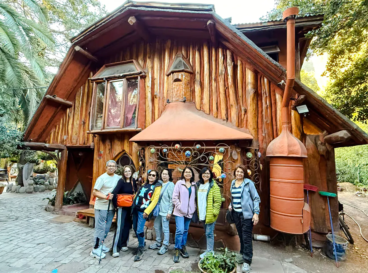 Group of tourists in front of a rustic wooden cabin in Cajon del Maipo, Santiago.