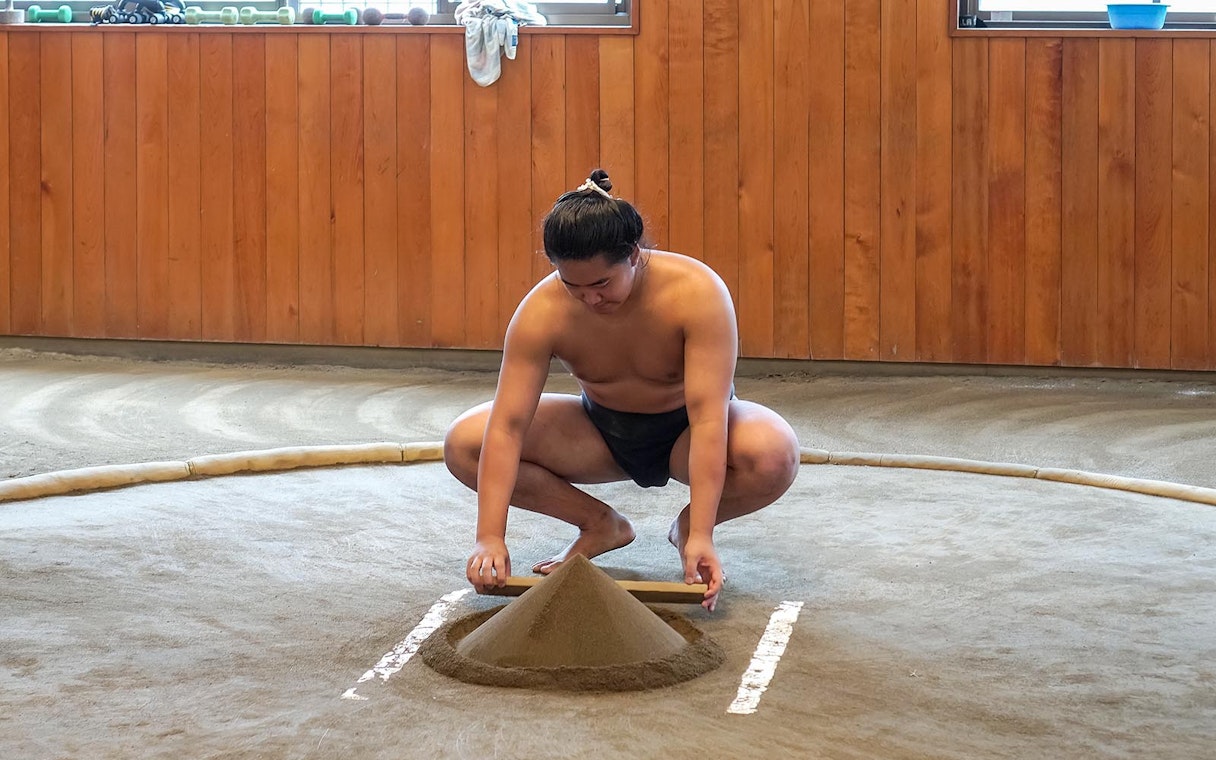 Sumo wrestler preparing practice ring at a sumo stable in Japan.