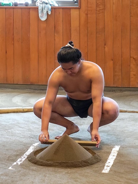 Sumo wrestler preparing practice ring at a sumo stable in Japan.